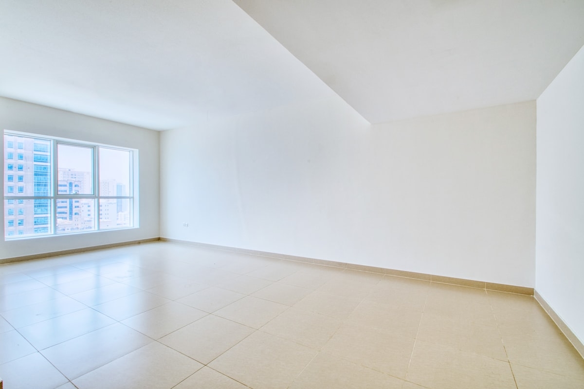 A spacious empty room with tiled floors and a large window ready for end of tenancy cleaning - Photo from Unsplash