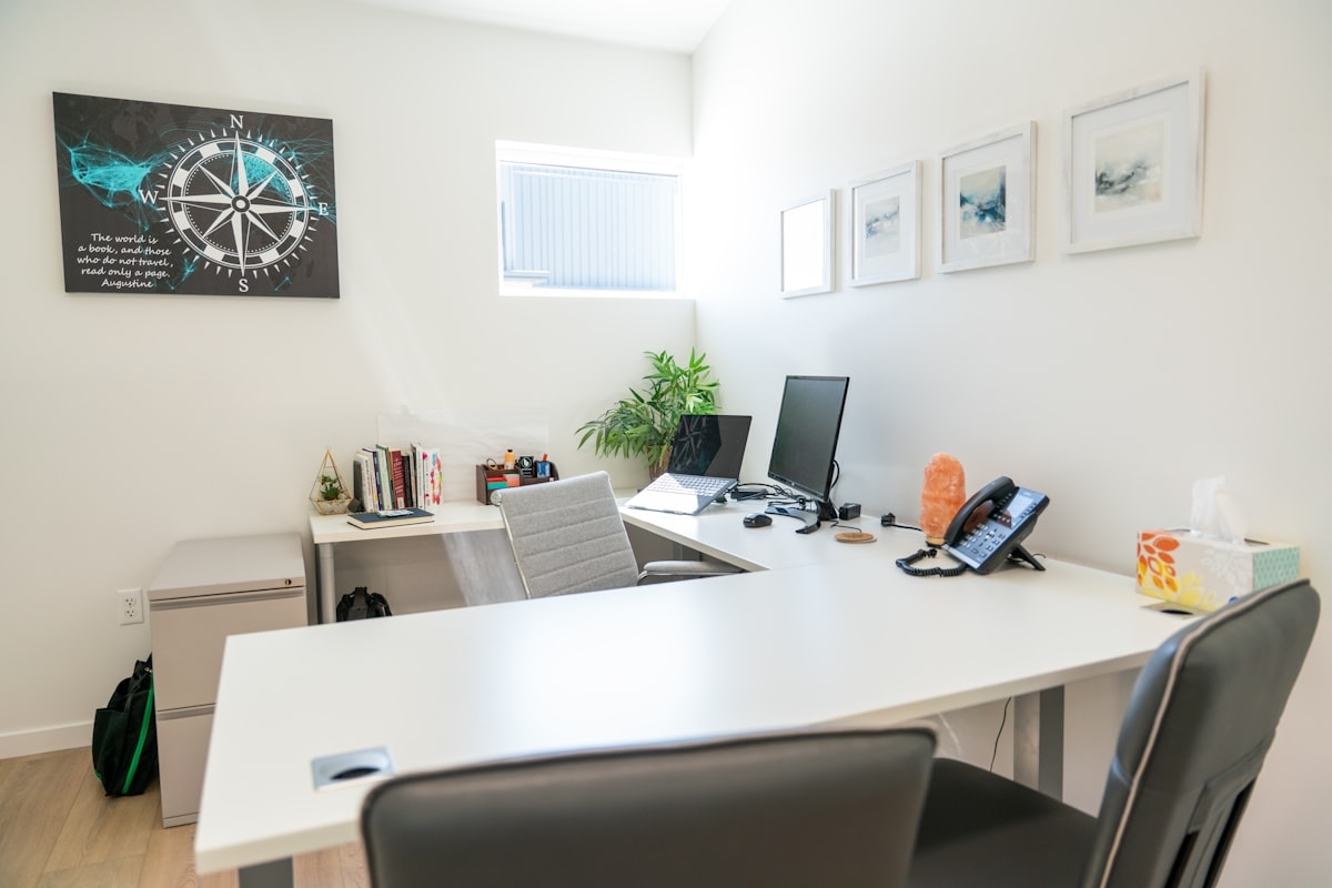 A clean and tidy modern office with a desk, computer, phone and artwork on the walls - Photo from Unsplash